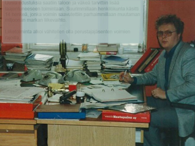 Toimistotyöntekijä Arto Louhio istuu työpöytänsä ääressä papereiden ja puhelimien keskellä silkkitehtaan konttorissa 1980-luvulla.